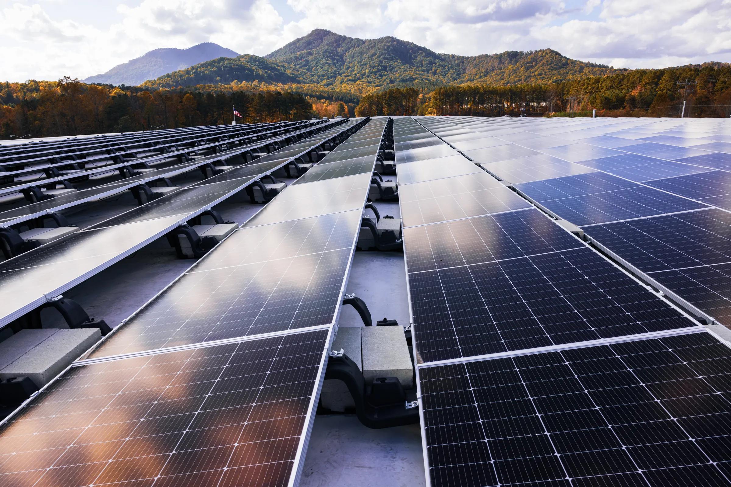 Commercial rooftop solar array on a Sollega ballasted racking system stretching toward a mountain horizon